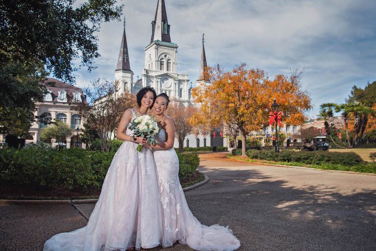 Lesbian couple in Jackson Square with New Orleans' St. Louis Cathedral in the background. Wedding Photography by The Red M Studio.